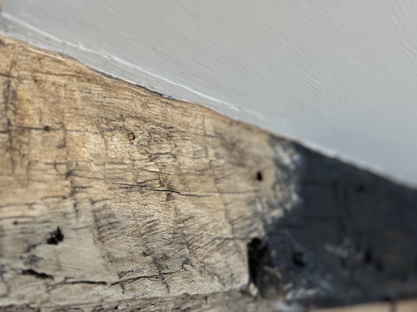 Oak beam part-way through treatment, lightened on one side and still black on the other
