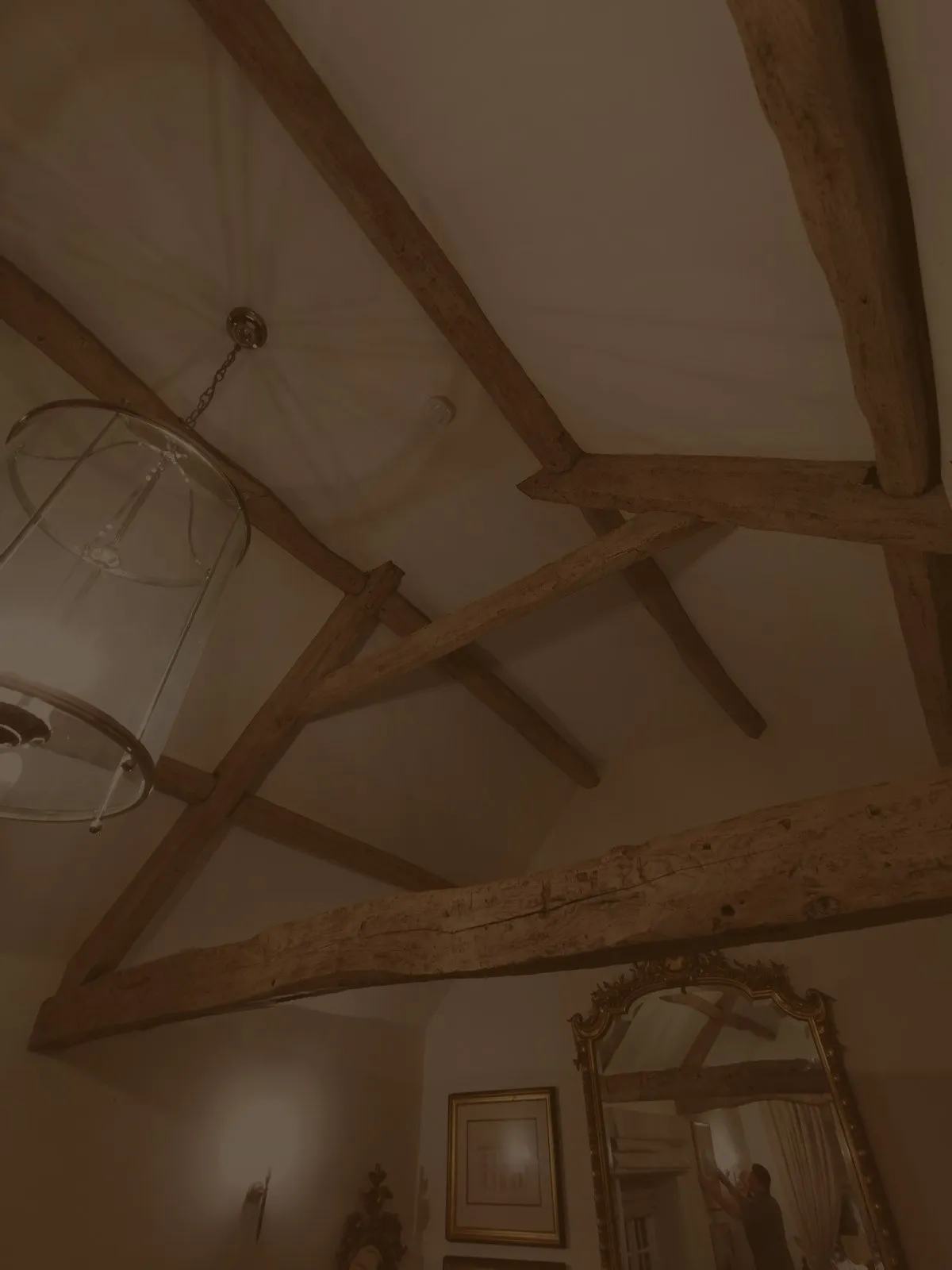 A vaulted period ceiling of exposed oak beams and trusses, lit by a lantern pendant